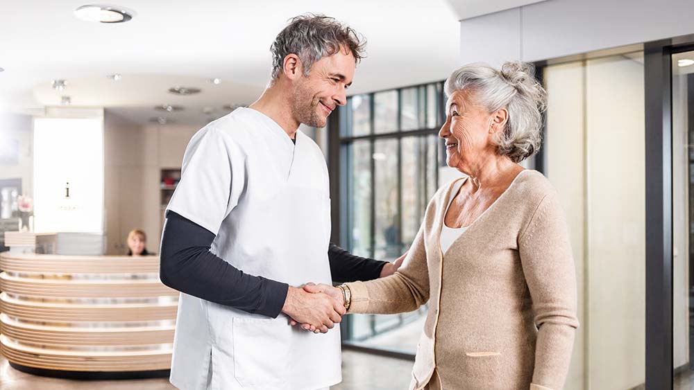 Un médecin se serre la main d’un patient, en arrière-plan se trouve une zone d’accueil