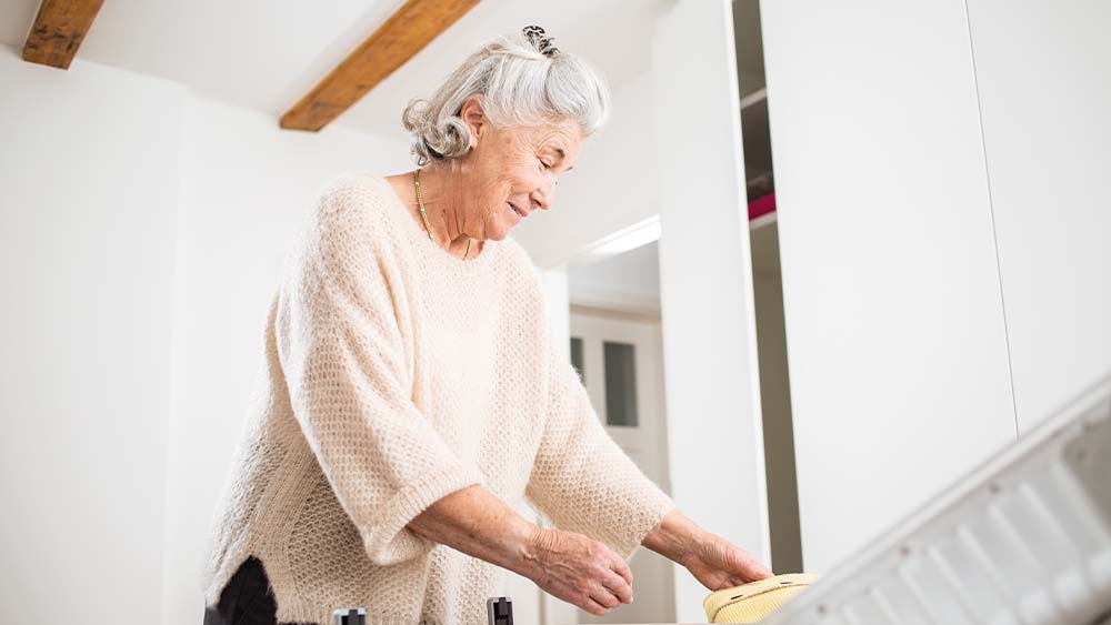 Une femme âgée fait ses valises et sourit