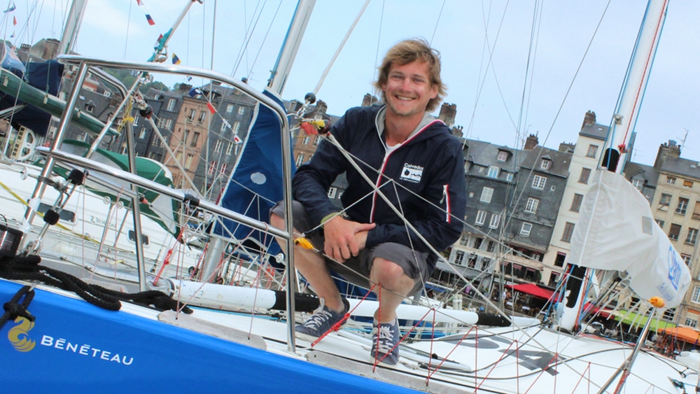 Un homme souriant sur un bateau, des maisons en arrière-plan